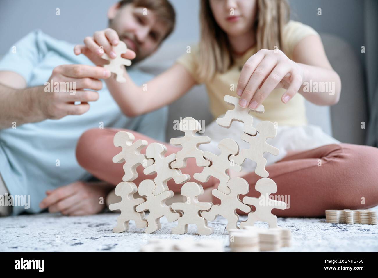 Vater hilft der Tochter, zu Hause Holzrätsel zu stapeln Stockfoto