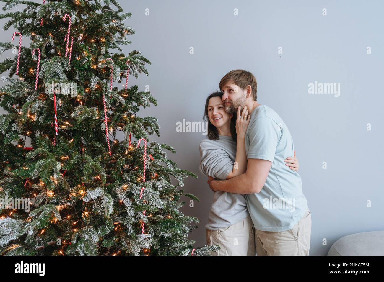 Ein Paar umarmt sich und schaut sich den Weihnachtsbaum an Stockfoto