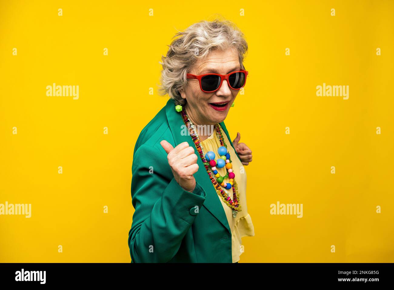 Coole Seniorin mit Blazer-Jacke vor gelbem Hintergrund Stockfoto