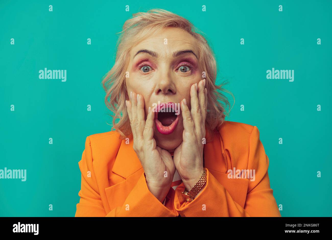 Schockierte Seniorin vor türkisfarbenem Hintergrund Stockfoto