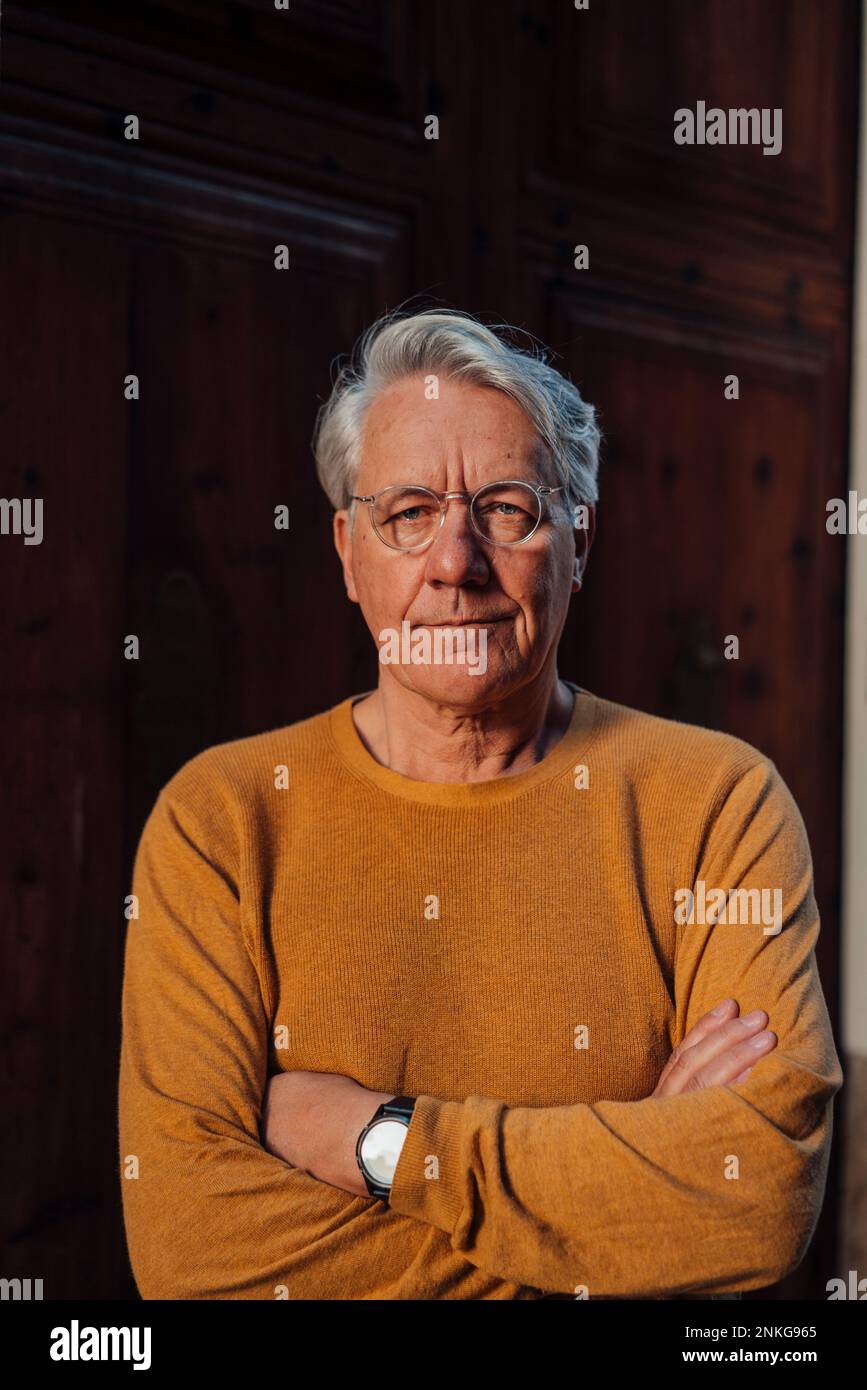 Ein älterer Mann, der mit verschränkten Armen steht Stockfoto