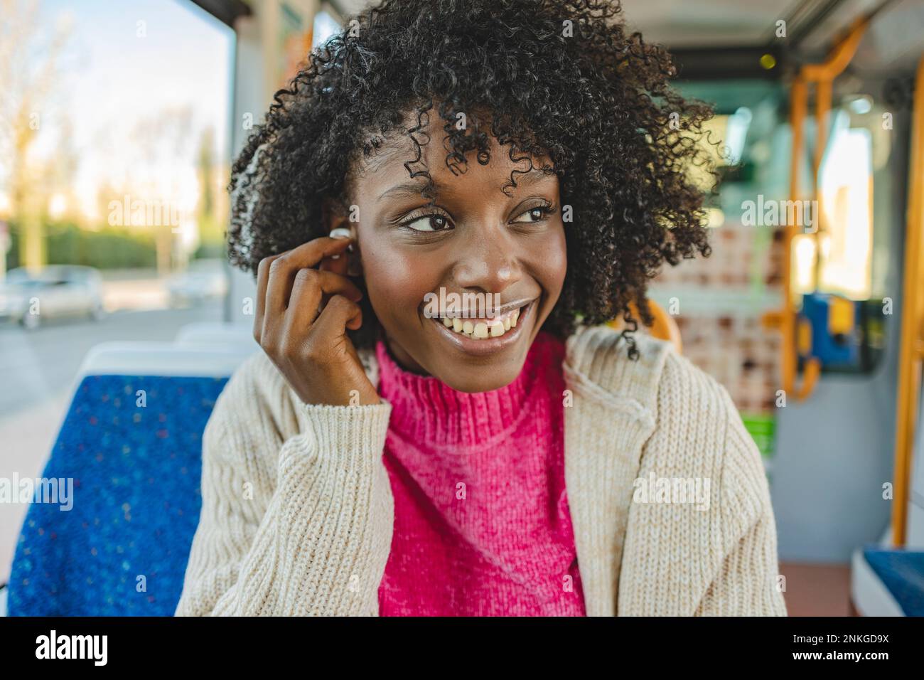 Glückliche Frau mit kabellosen InEar-Kopfhörern in der Straßenbahn Stockfoto