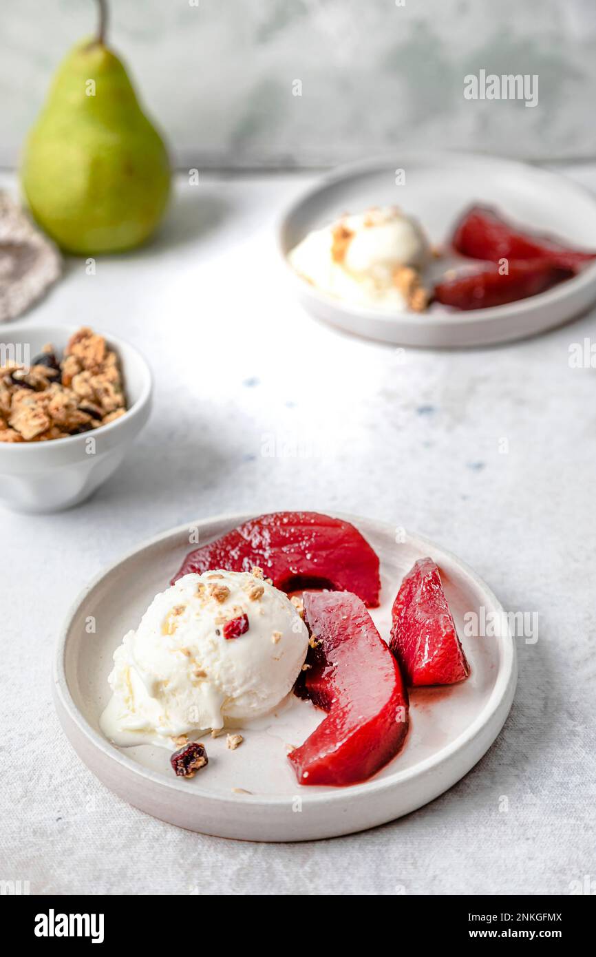 Birnen in Rotwein mit Eiscreme auf dem Tisch Stockfoto