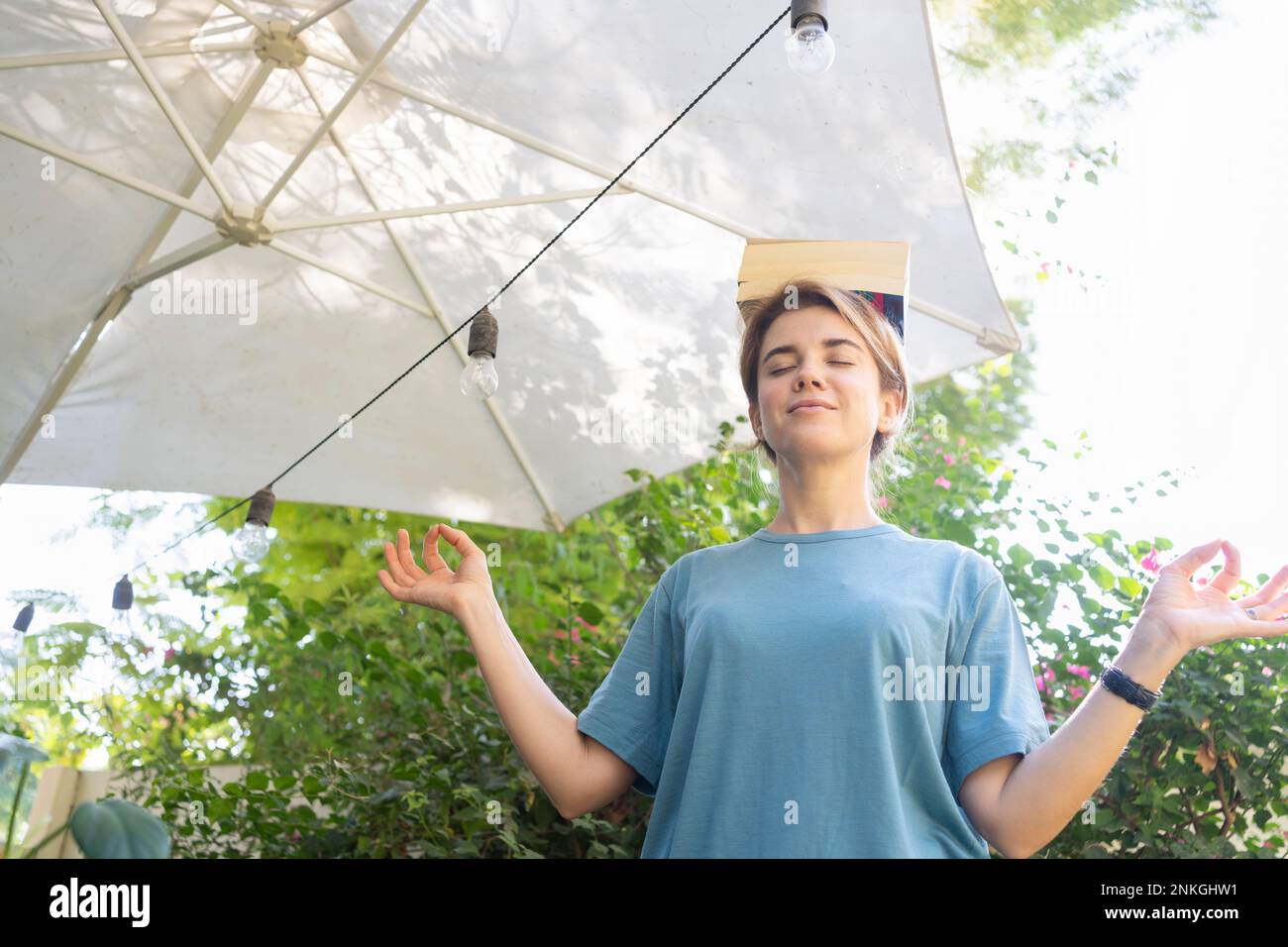 Eine Frau, die Bücher auf dem Kopf im Garten ausbalanciert Stockfoto