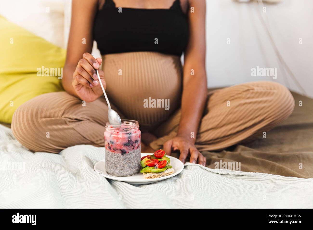 Schwangere Frau, die zu Hause ein gesundes Frühstück isst Stockfoto