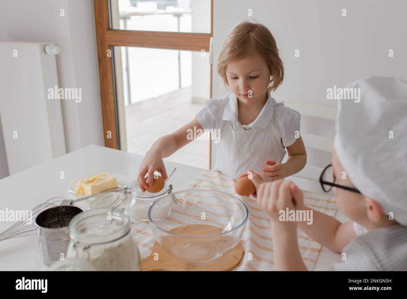 Kinder brechen Eier in der Mischschüssel Stockfoto