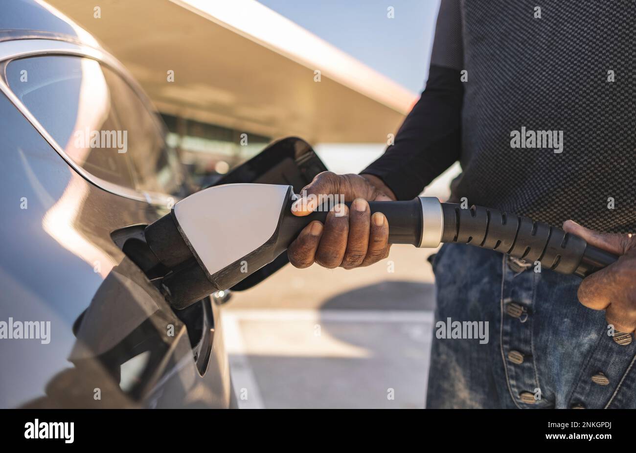 Hände eines Mannes, der den Stecker in ein Elektroauto steckt Stockfoto