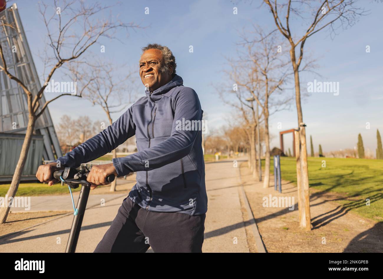 Rücksichtsvoller Senior-Mann, der an sonnigen Tagen mit einem elektrischen Roller fährt Stockfoto