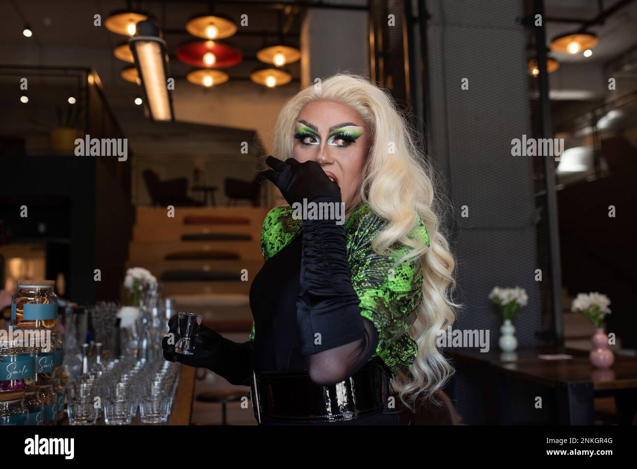 Eine blonde Drag Queen, die Wodka in der Bar serviert Stockfoto