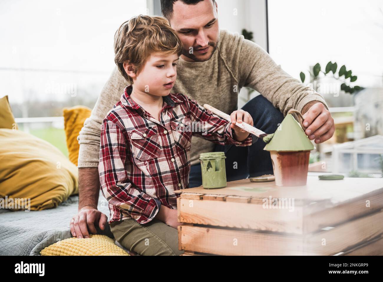 Vater hilft Sohn, Modellhaus zu Hause zu malen Stockfoto