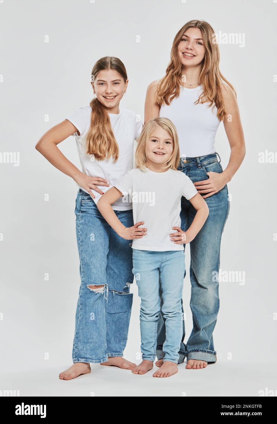 Fröhliche Schwestern tragen lässige Kleidung vor weißem Hintergrund Stockfoto