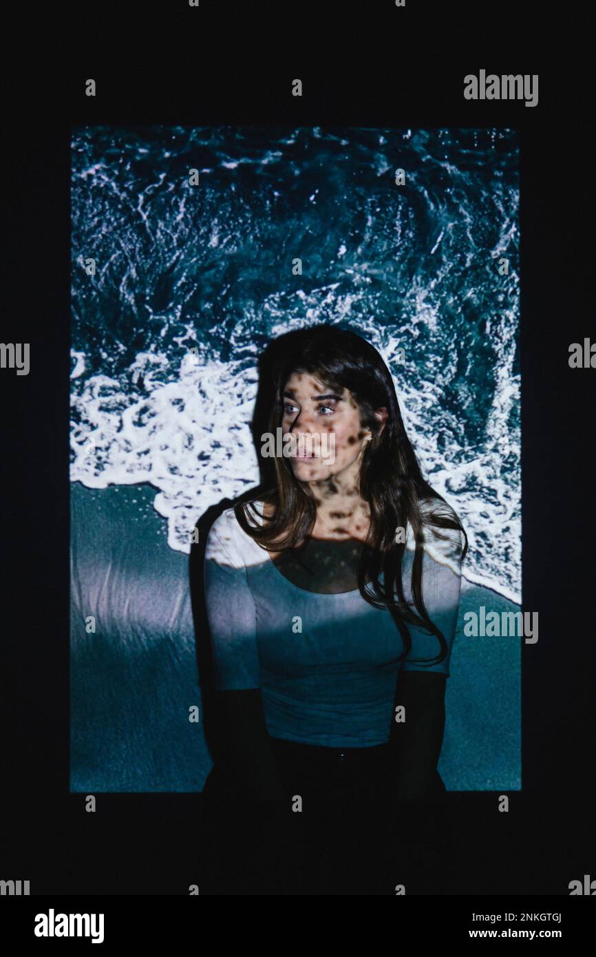 Projektion der Meereswelle auf eine kontemplative junge Frau Stockfoto