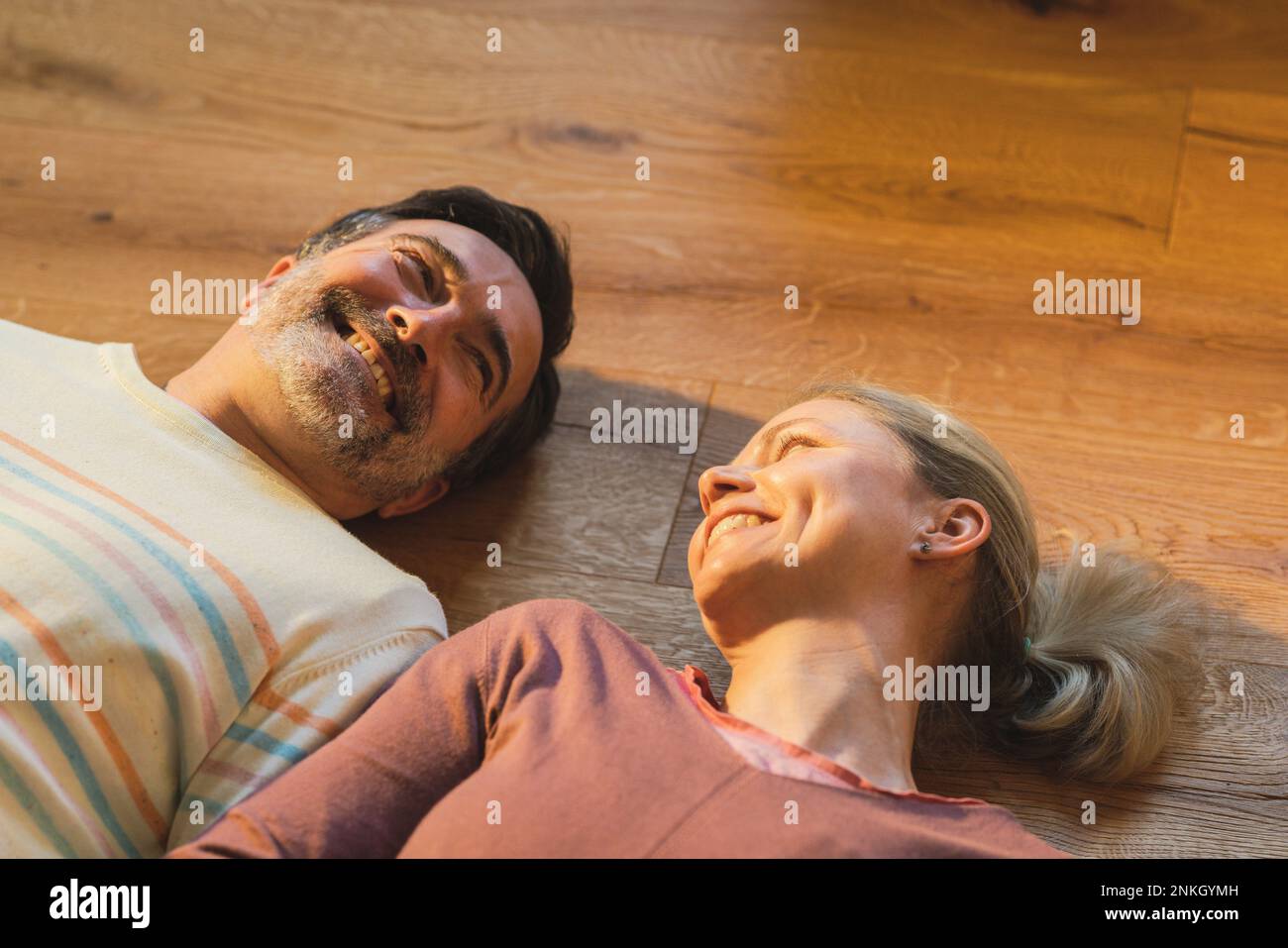 Glückliches Paar, das zu Hause auf dem Parkettboden lag Stockfoto