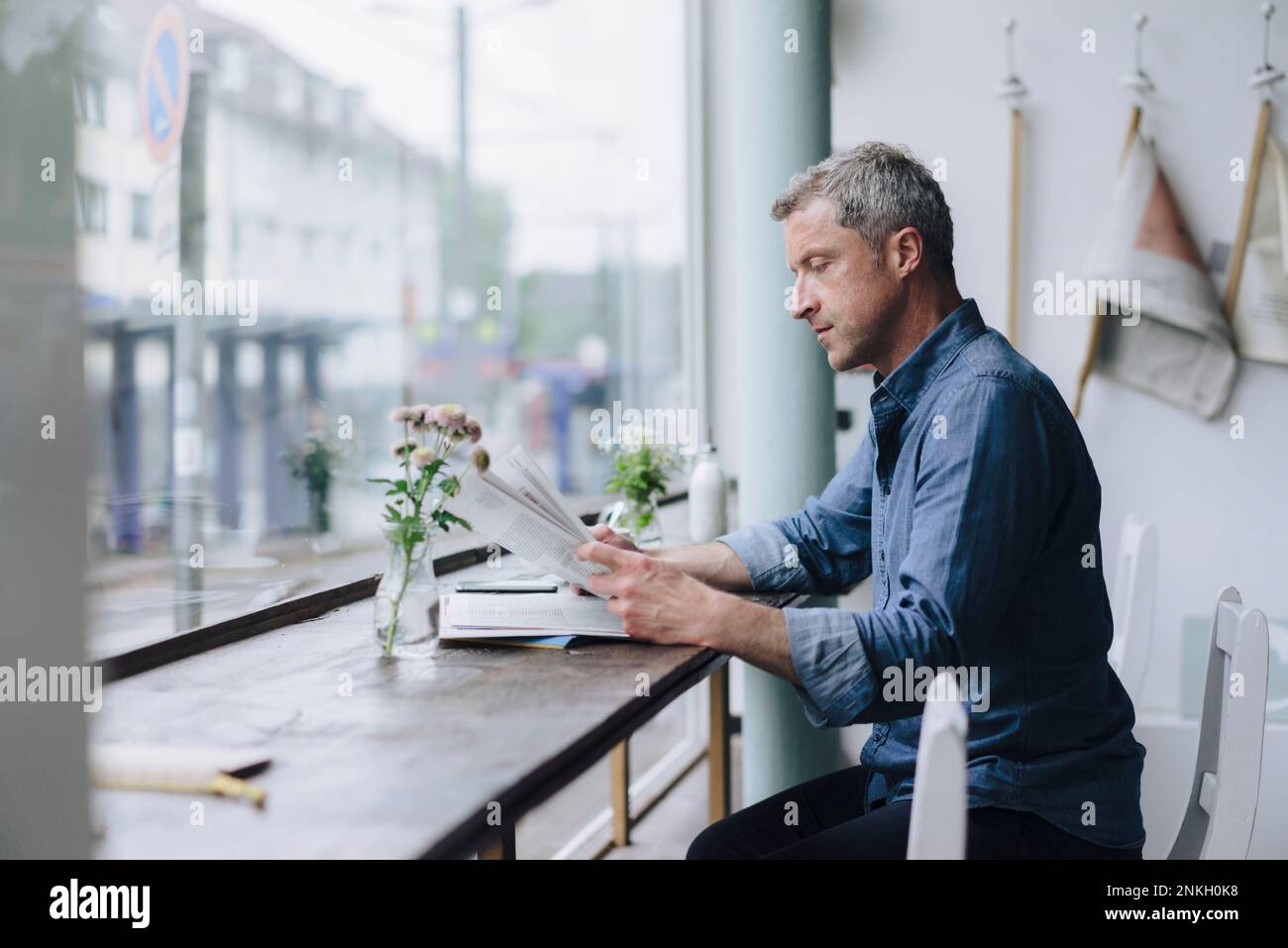 Ein Geschäftsmann, der Zeitung liest, sitzt im Café Stockfoto