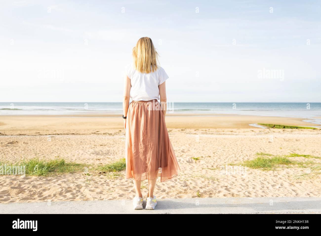 Eine Frau, die an sonnigen Tagen am Strand steht Stockfoto