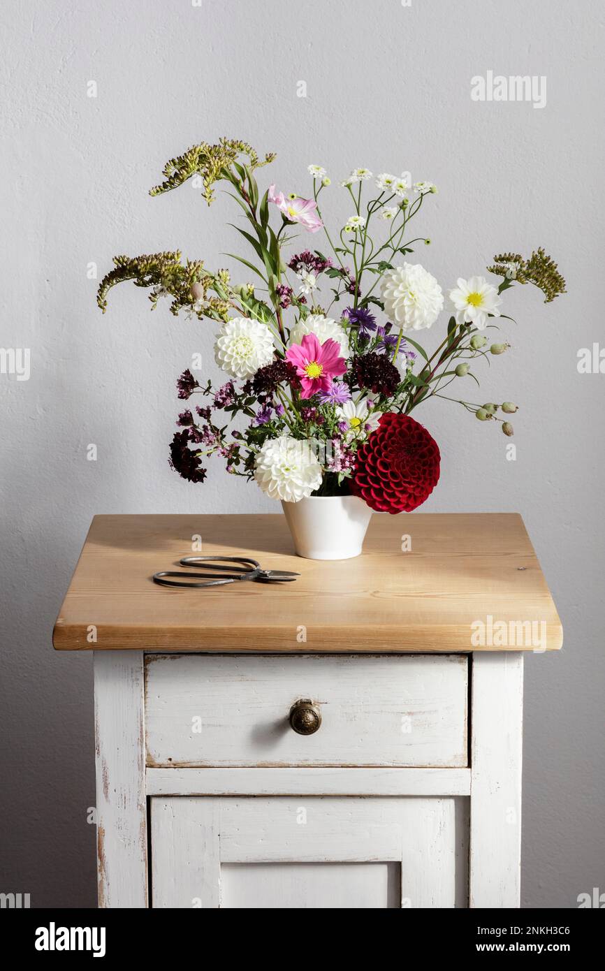 Anordnung von Kräutern und blühenden Herbstblumen auf dem Nachttisch Stockfoto