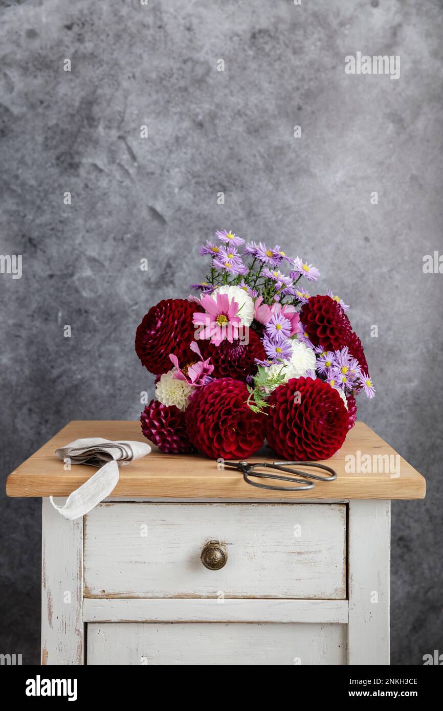 Strauß roter und rosafarbener Blumen der Saison auf dem Nachttisch Stockfoto