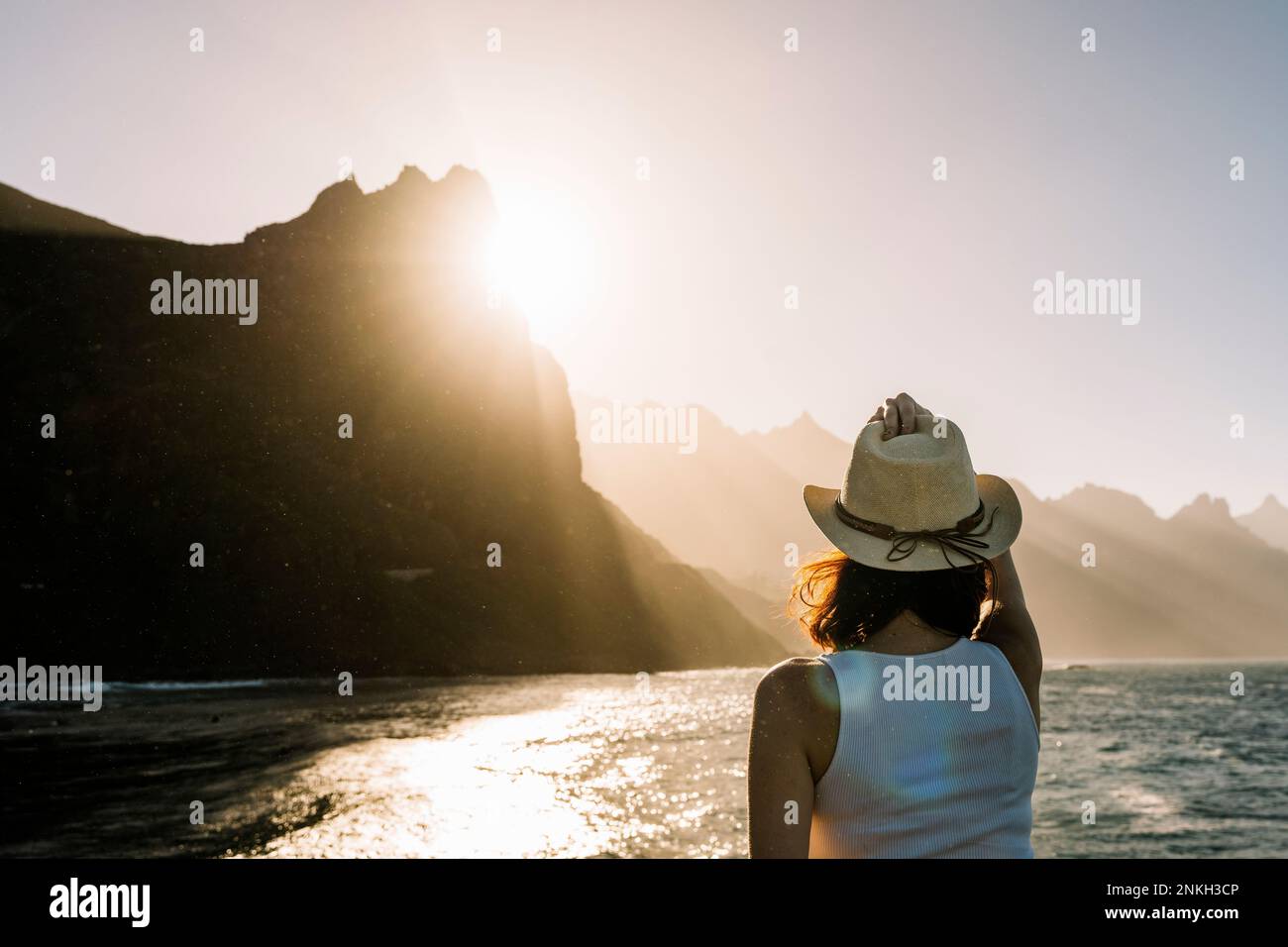 Spanien, Kanarische Inseln, junge Frau, die den Sonnenuntergang über den Küstenbergen der Macizo de Anaga Range bewundert Stockfoto
