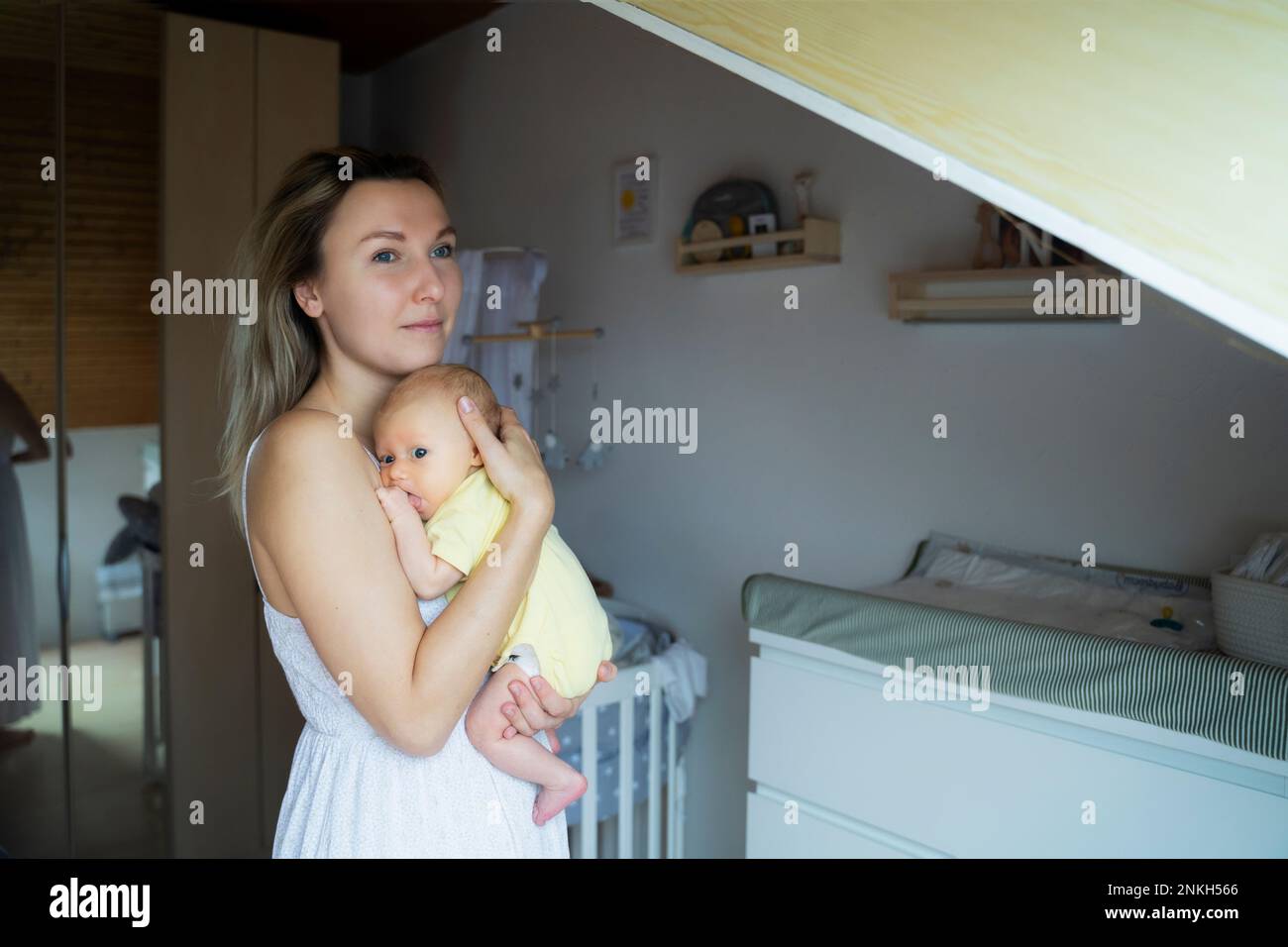 Kontemplative Mutter mit dem kleinen Jungen, der zu Hause steht Stockfoto