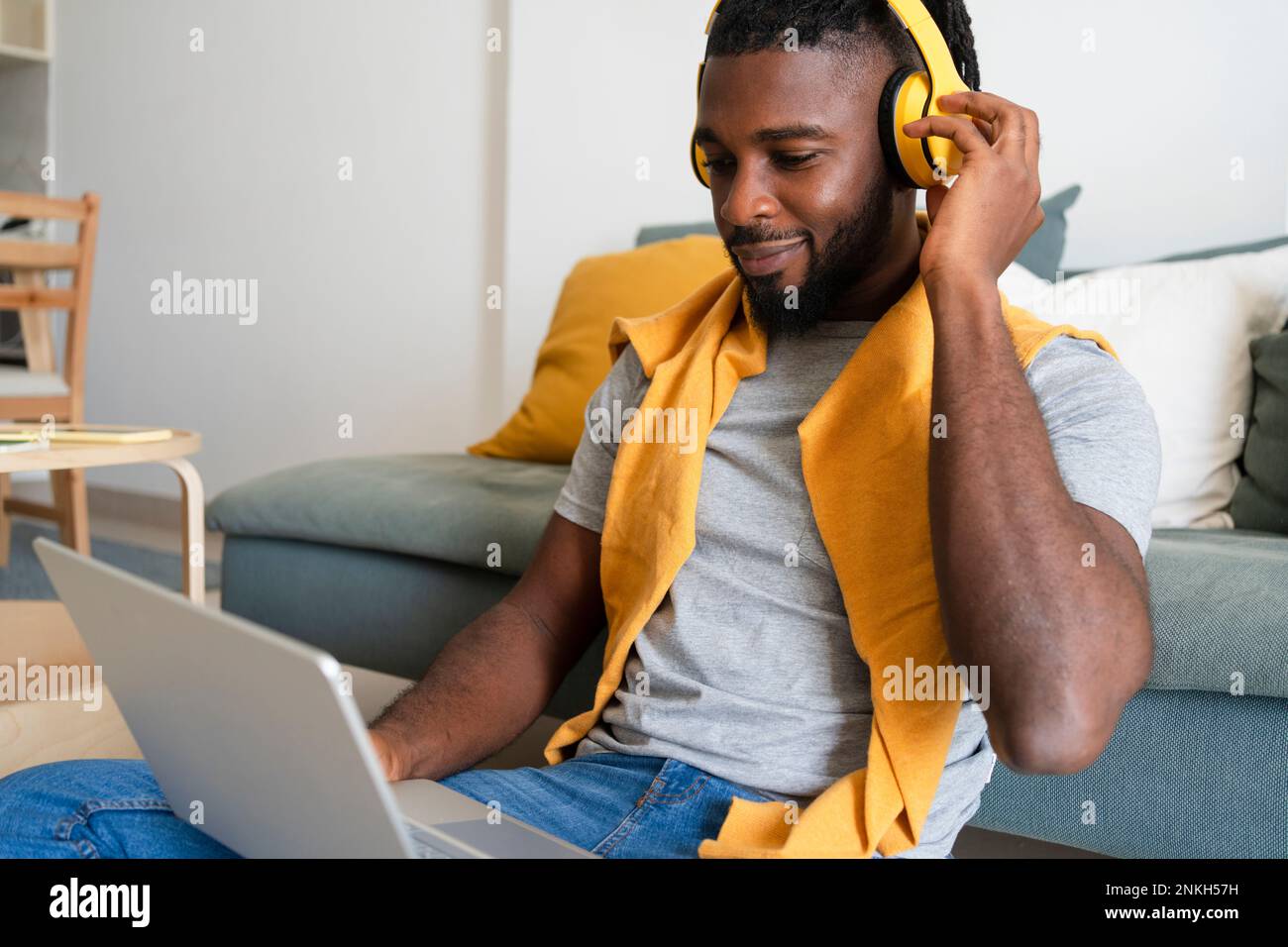 Freiberufler trägt kabellose Kopfhörer und arbeitet auf einem Laptop Stockfoto