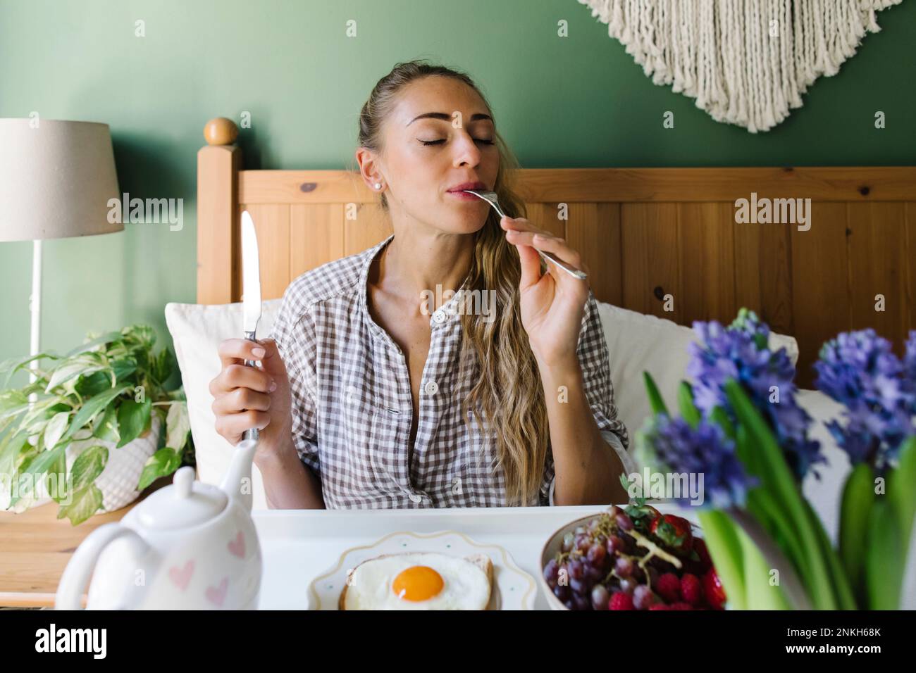 Frau, die das Frühstück zu Hause im Bett genießt Stockfoto