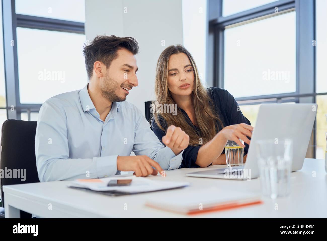 Geschäftsfrau, die gemeinsam mit einem Kollegen über ein Notebook am Arbeitsplatz eine Strategie plant Stockfoto