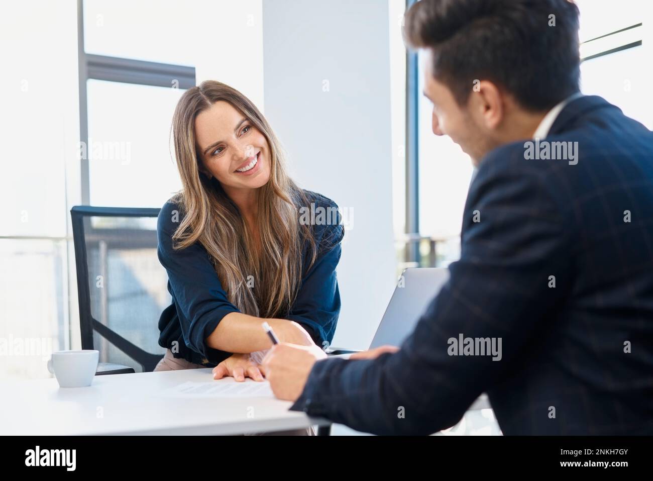 Glückliche Geschäftsfrau, die den Einstellungsprozess mit dem Kandidaten im Amt abschließt Stockfoto