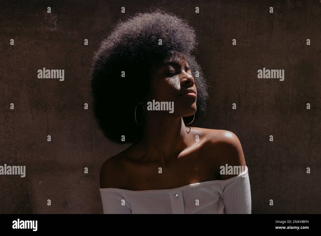 Junge Frau mit geschlossenen Augen, die ein Schulteroberteil trägt Stockfoto