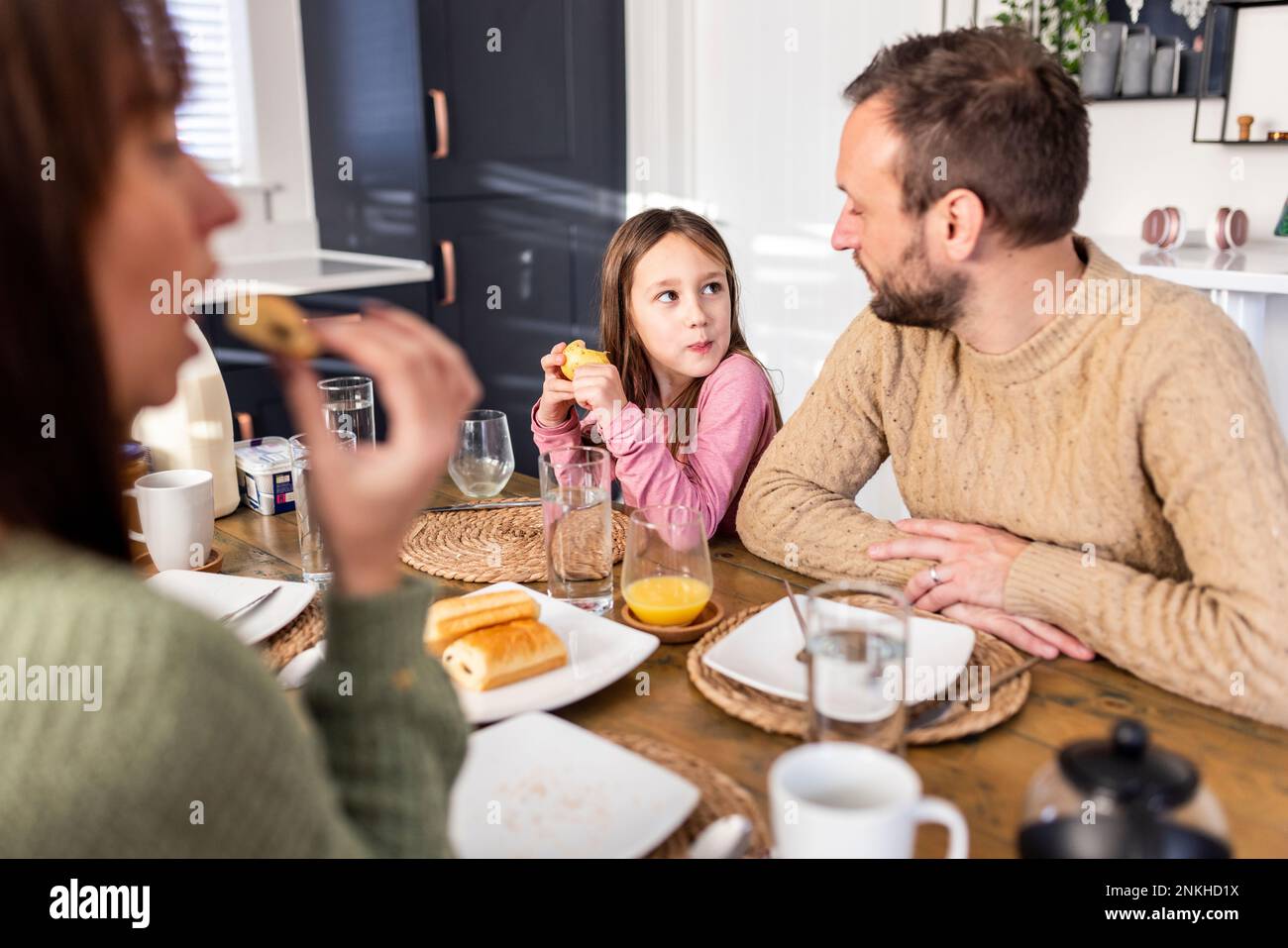 Ein Mädchen frühstückt mit der Familie zu Hause Stockfoto