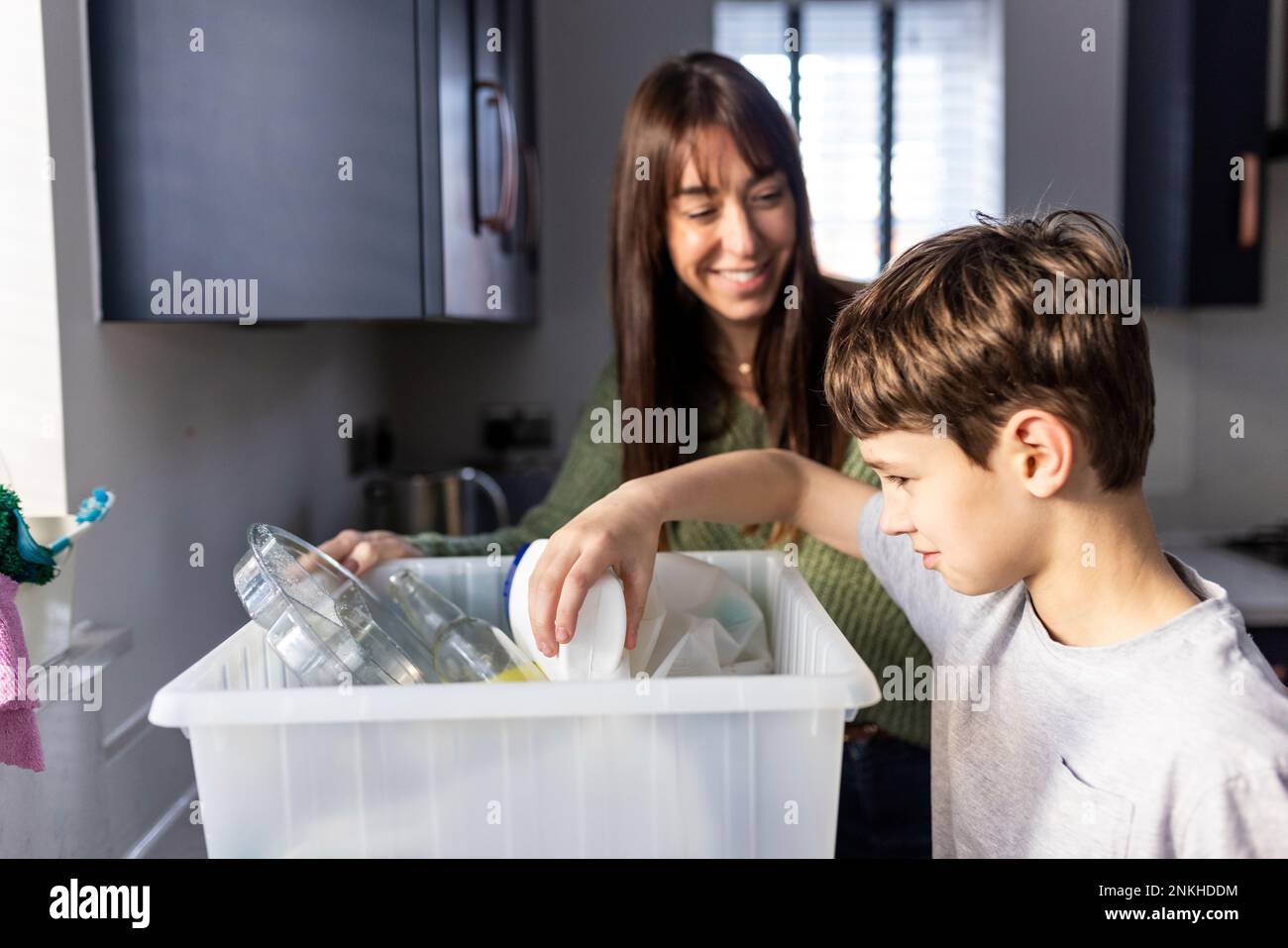 Glückliche Frau mit einem Jungen, der Plastikflaschen zu Hause recycelt Stockfoto