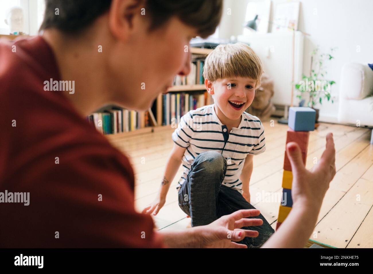 Glücklicher Junge, der Spielzeugblöcke mit Mutter zu Hause spielt Stockfoto