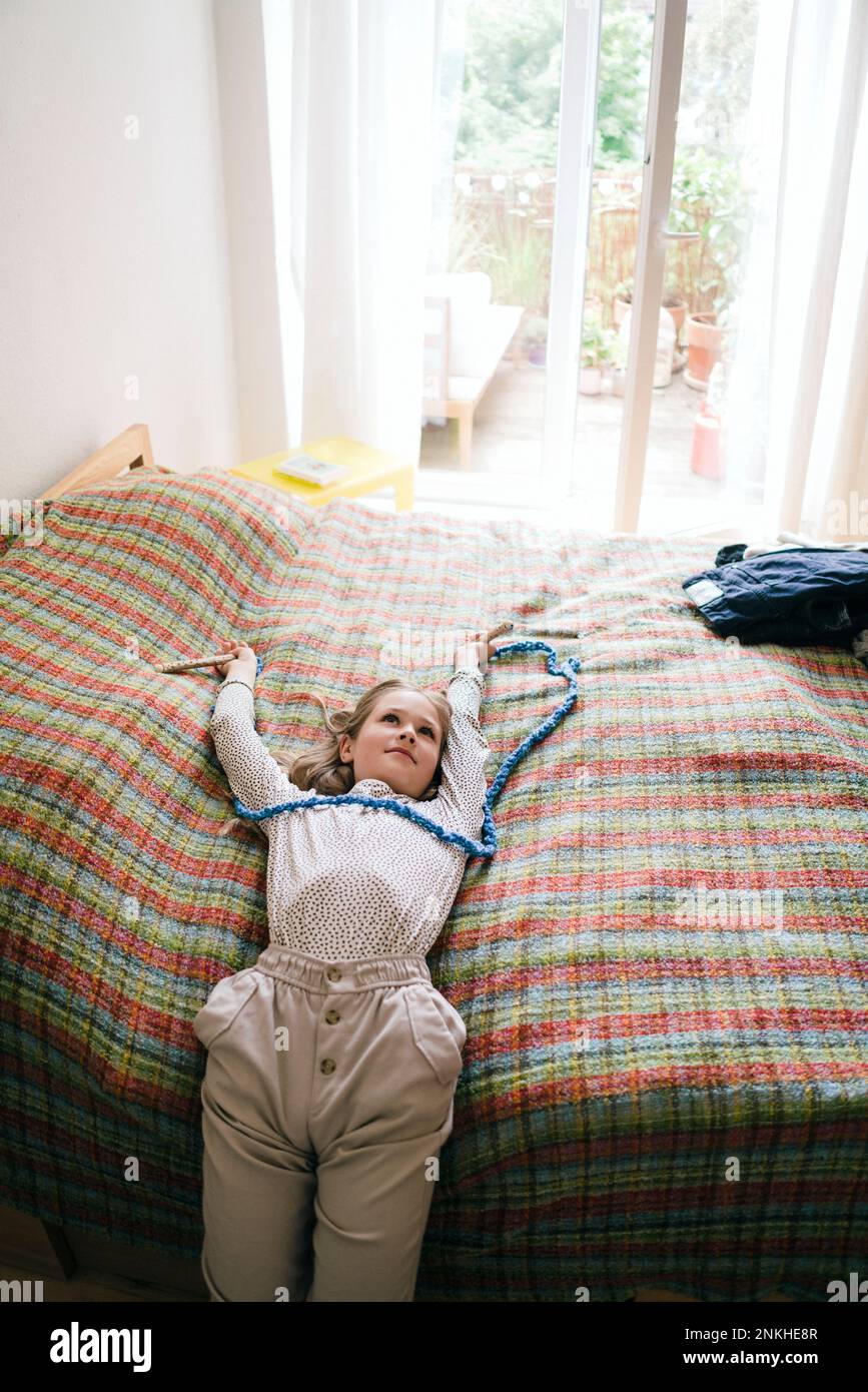 Ein Mädchen mit erhobenen Armen liegt zu Hause auf dem Bett Stockfoto