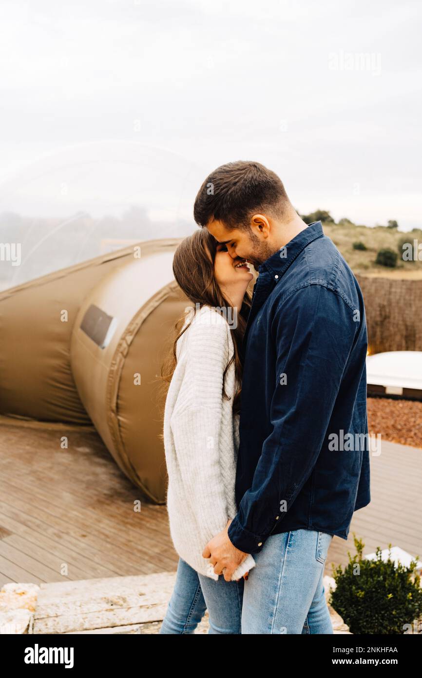 Glückliches junges Paar, das sich im Kuppelzelt küsst Stockfoto