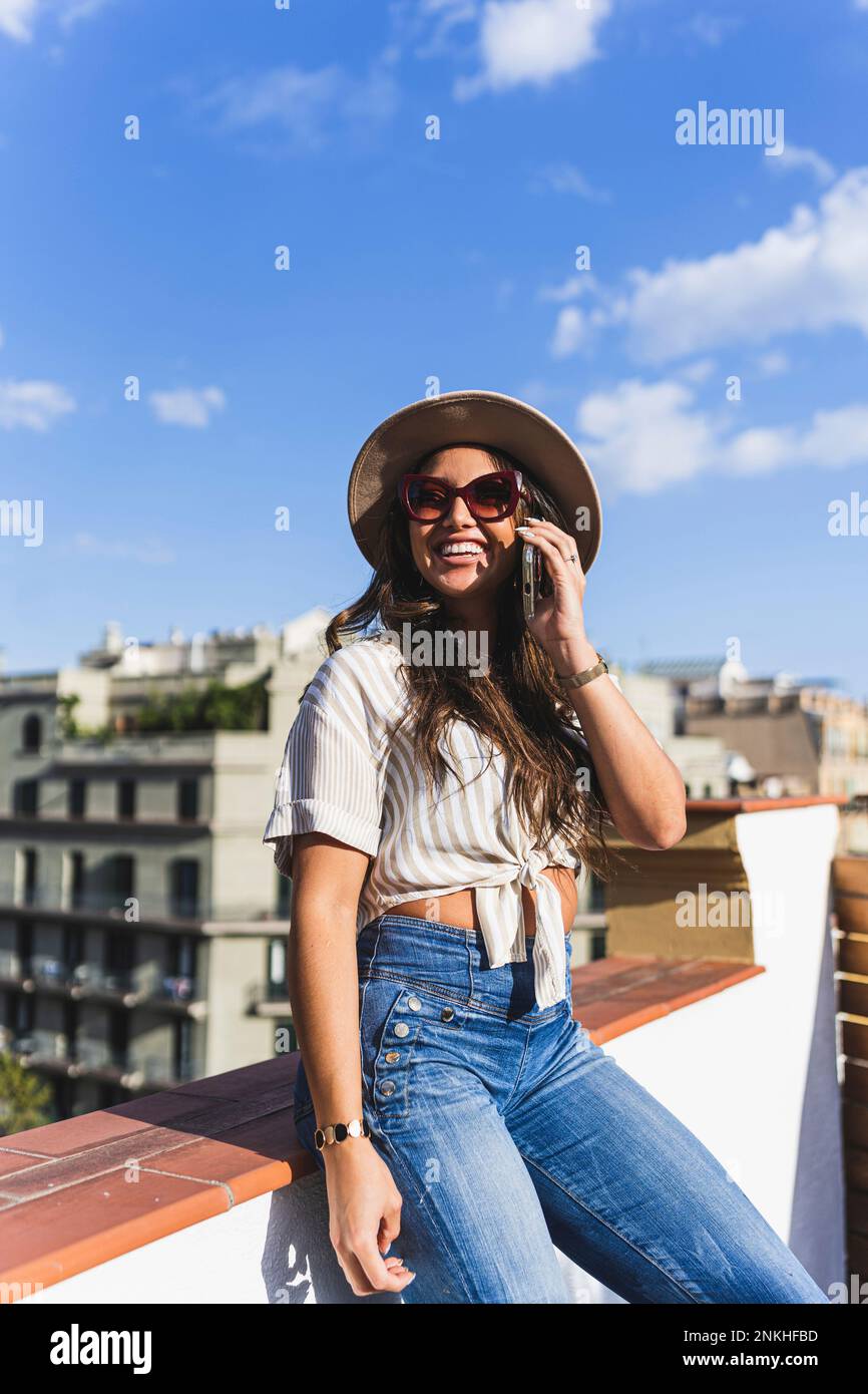 Lächelnde Frau, die unter dem Himmel auf einem Smartphone spricht Stockfoto