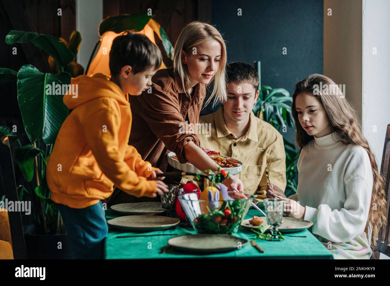 Eine Frau, die der Familie Essen serviert und zu Hause Ostern isst Stockfoto
