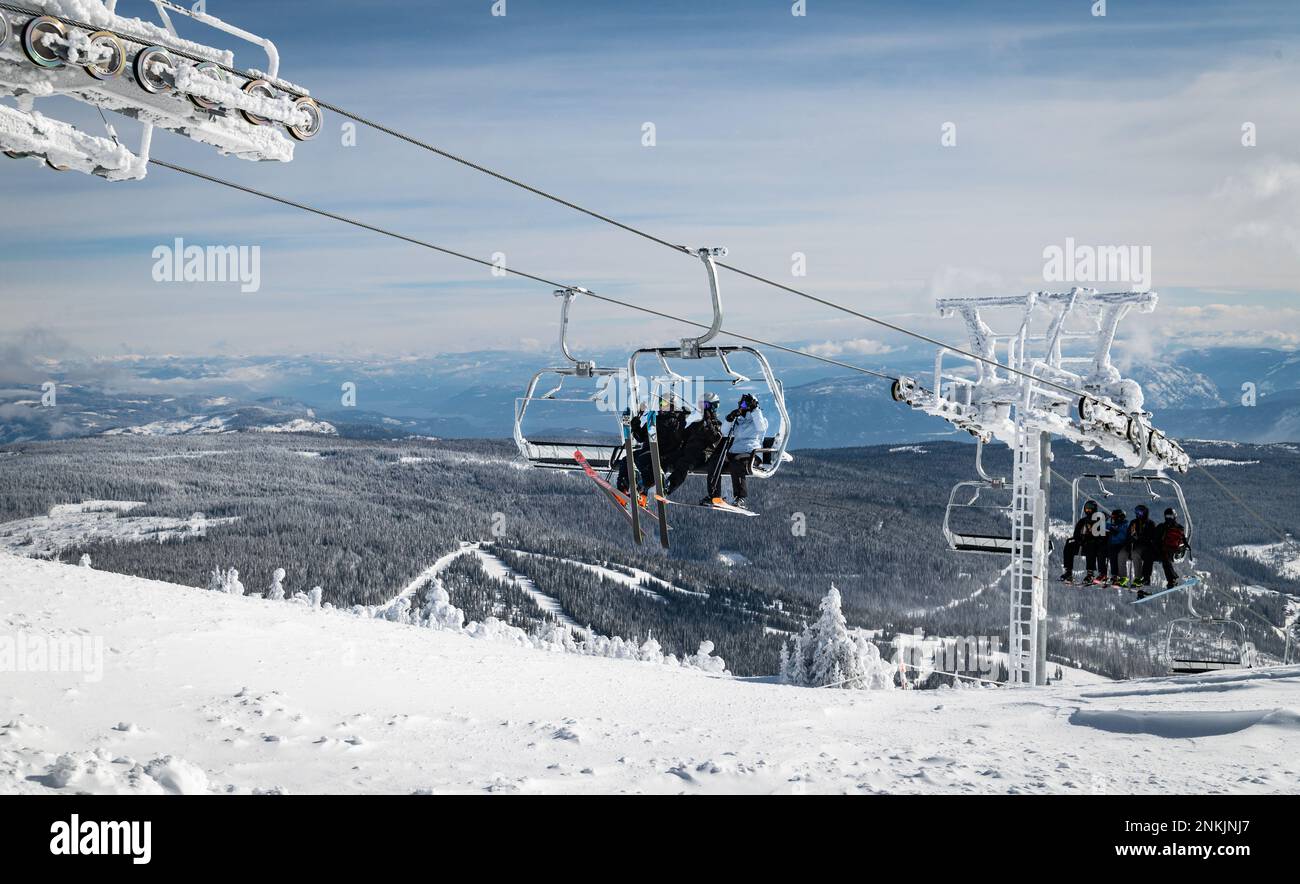 Skifahrer und Snowboarder bereiten sich an einem sehr kalten Wintertag auf den Ausstieg aus dem Crystal Sessellift am „Top of the World“ im Sun Peak Ski Resort vor. Stockfoto