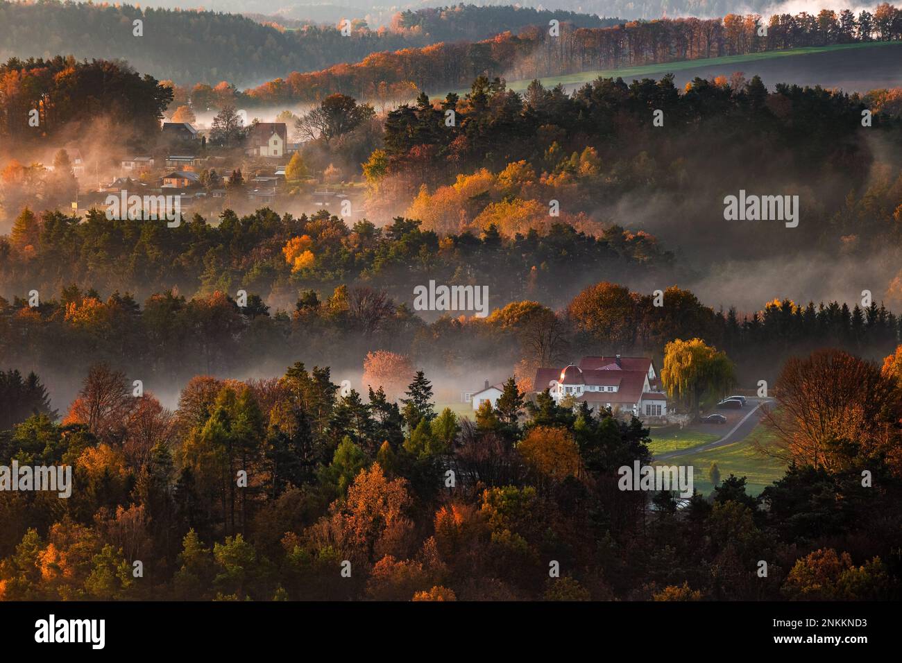 Sachsen, Deutschland - im sächsischen Schweizer Nationalpark geht die Sonne im warmen, nebligen Herbst über dem Tal auf, mit frischem, lebhaftem Herbstlaub und Nebel auf den Feldern Stockfoto
