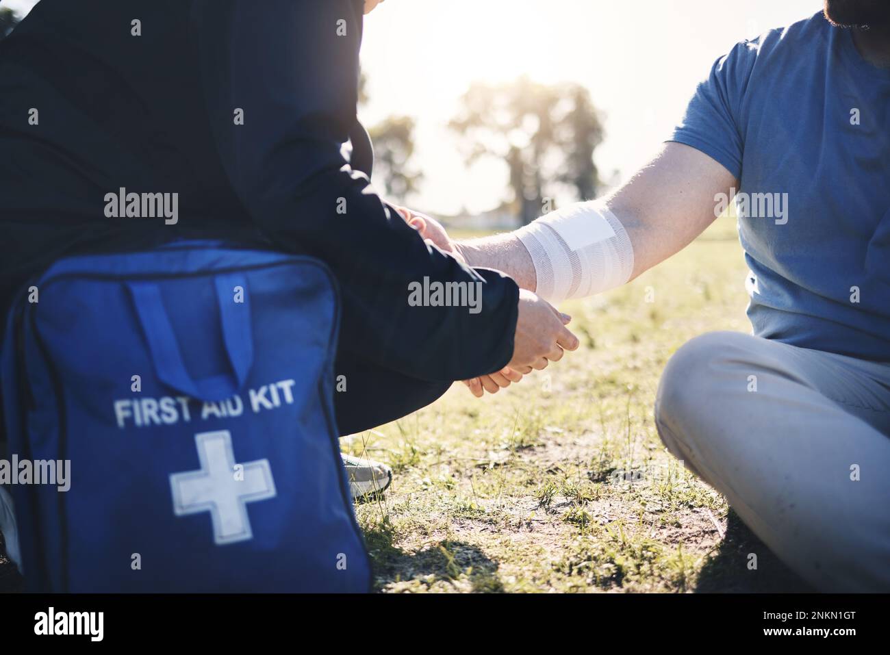 Erste Hilfe, Hilfe und Armverletzung durch Mann mit Sanitäter am Boden während der morgendlichen Kardiologie im Freien. Sanitäter, Notdienst und verletzte männliche mit Stockfoto