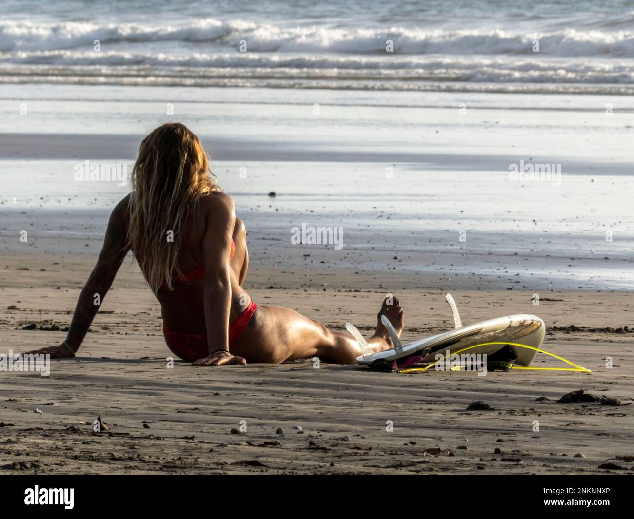 Eine Surferin macht eine Pause mit ihrem Surfbrett neben ihr am Strand von Nosara Costa Rica Stockfoto