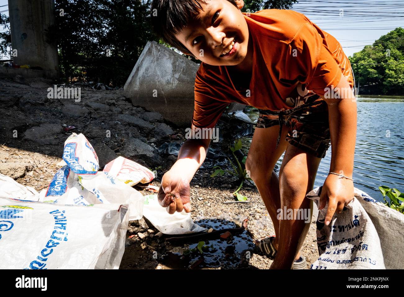 Lad Krabang, Thailand, 24/02/2023, Ein Junge zeigt eine winzige Krabbe, die er im Kanal gefunden hat. Das tägliche Leben rund um Lad Krabang, ein Wohnviertel in der Nähe des internationalen Flughafens Suvarnabhumi, in East Bangkok, Thailand, am 24. Februar 2022. Stockfoto