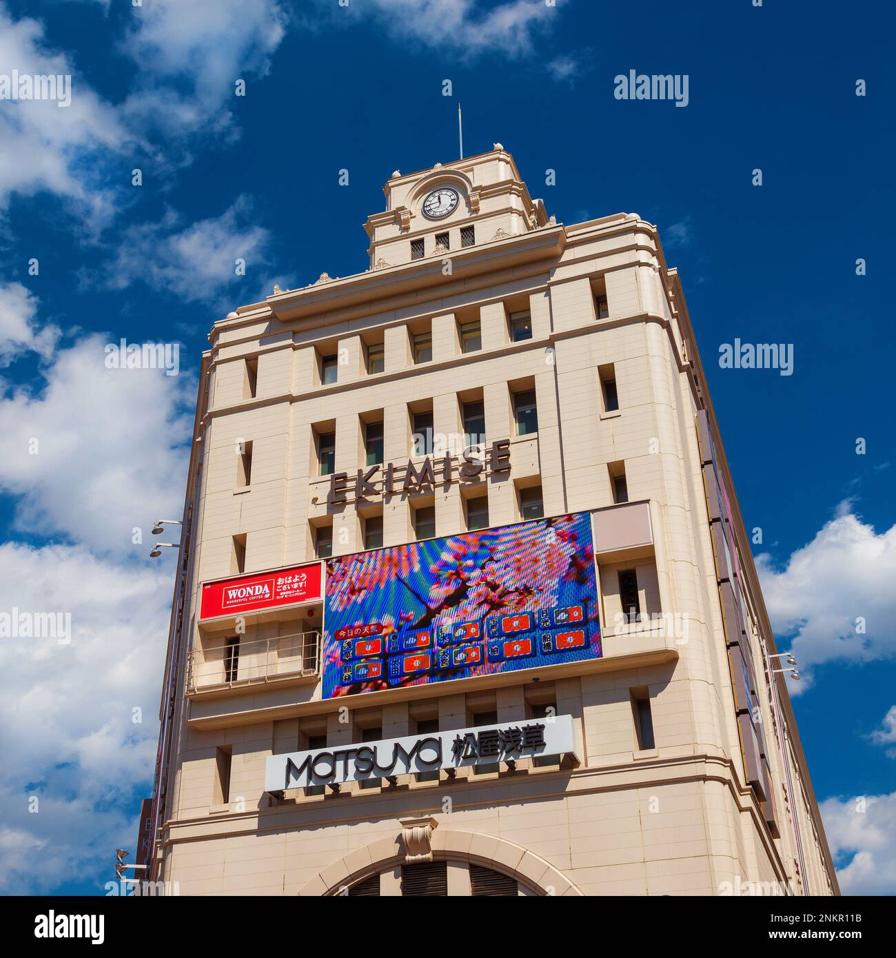 Frühling in Japan. Einkaufszentrum Ekimise und Bahnhof, ein renoviertes Gebäude aus der Showa-Ära im Bezirk Asakusa, mit Wettervorhersage und Sakura Cherr Stockfoto