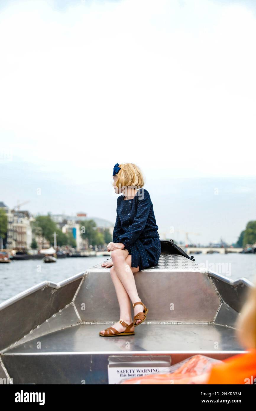 Ein Mädchen, das vor dem Boot sitzt und in die Ferne schaut Stockfoto