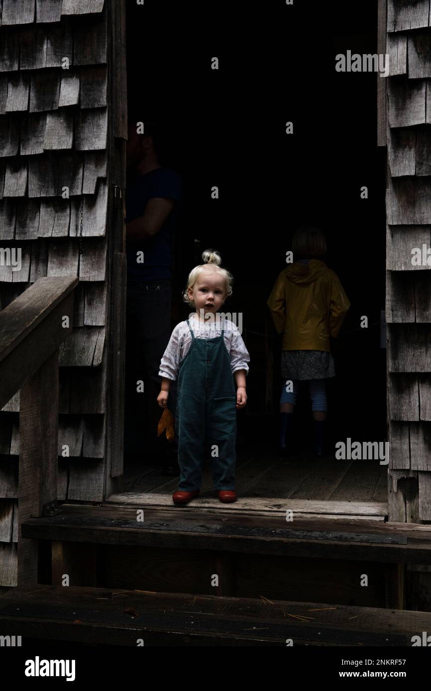 Ein junges Mädchen, das in einer Holzhütte steht Stockfoto