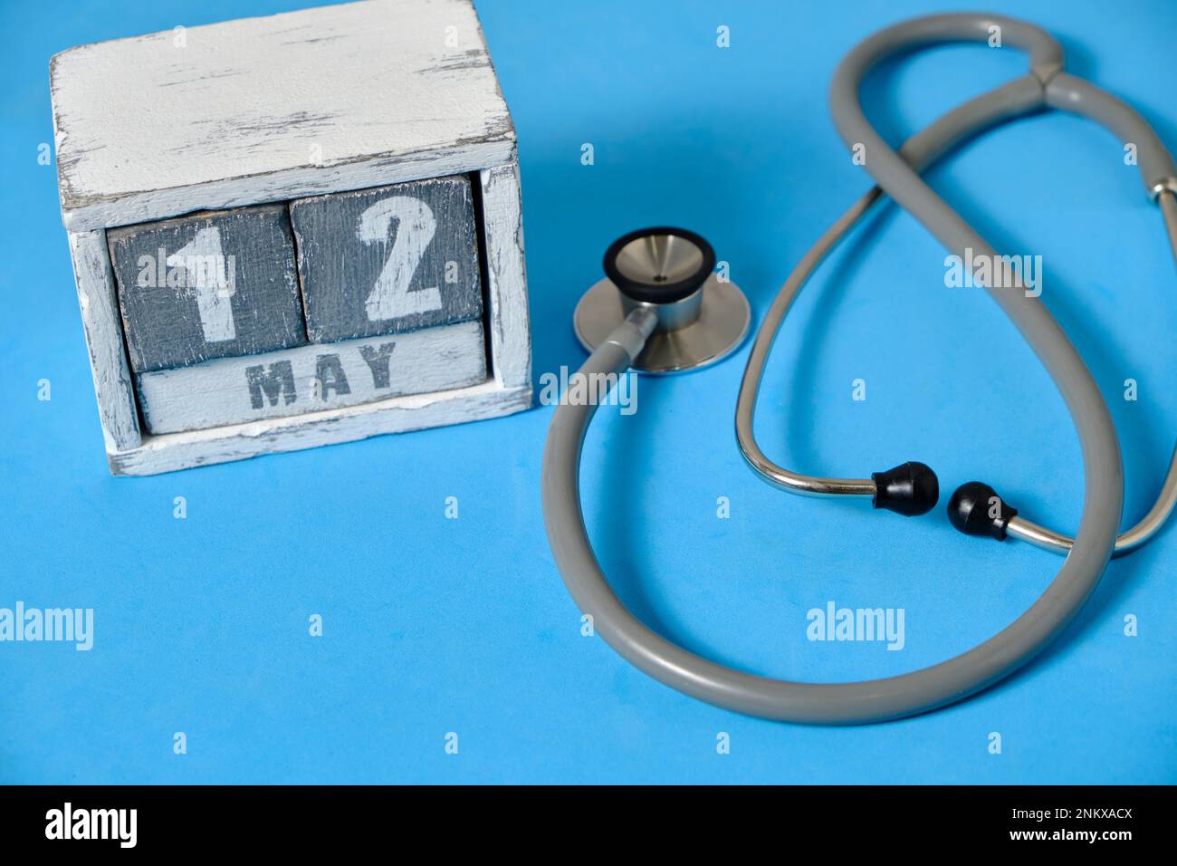 Mai 12, Holzkalender und Stethoskop auf blauem Hintergrund. Konzept für den Tag der Krankenschwester Stockfoto