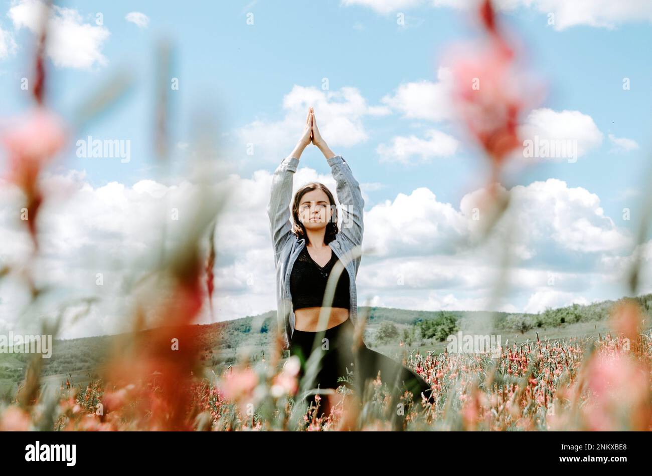 Eine Frau, die Yoga-Bäume auf dem Blumenfeld macht Stockfoto