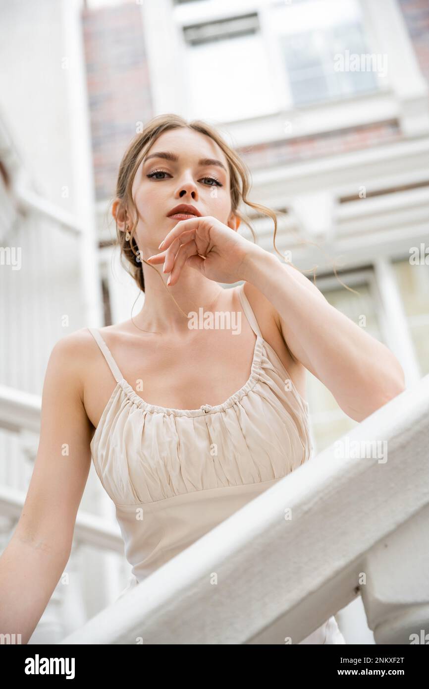 Kleiner Winkel von einer jungen Frau im Hochzeitskleid, die in der Nähe des Hauses auf die Kamera schaut, Stockbild Stockfoto