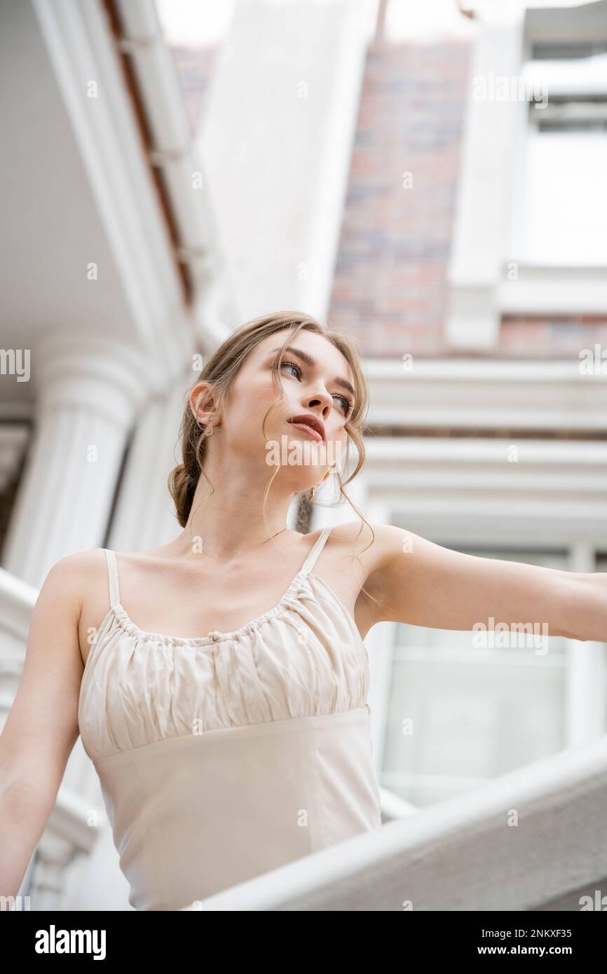 Kleiner Blickwinkel einer jungen Frau im Hochzeitskleid, die in die Nähe des Hauses blickt, Stockbild Stockfoto