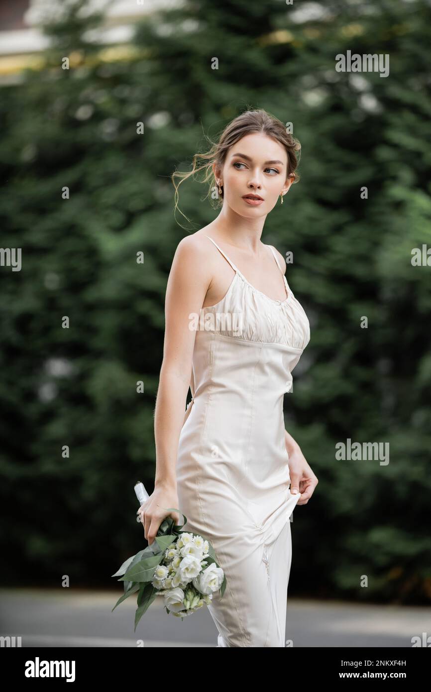 Junge Frau in Hochzeitskleid mit einem Blumenstrauß und Blick nach draußen, Stockbild Stockfoto