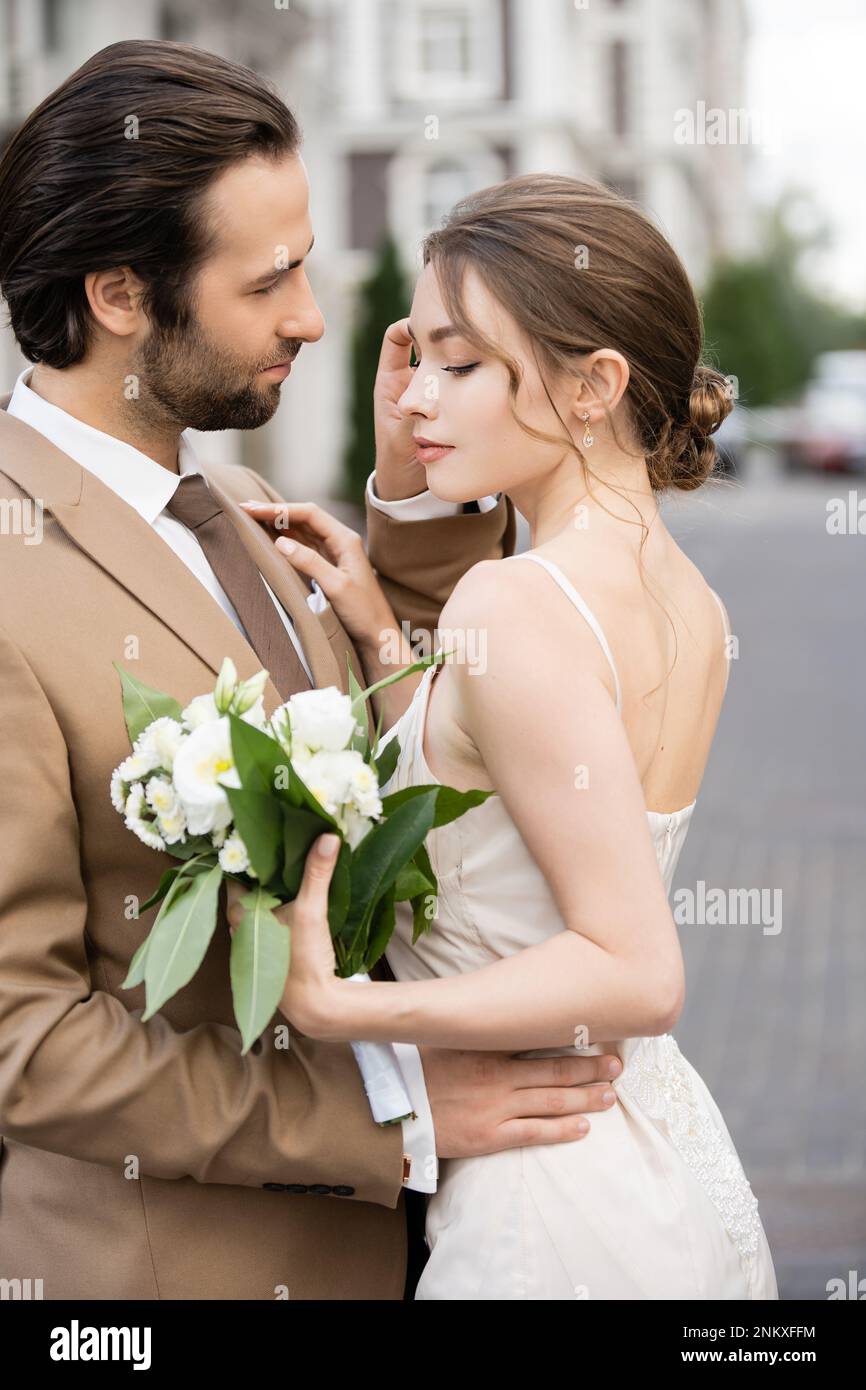 Hübsche Braut in Hochzeitskleid mit blühenden Blumen und mit Bräutigam, Stockbild Stockfoto