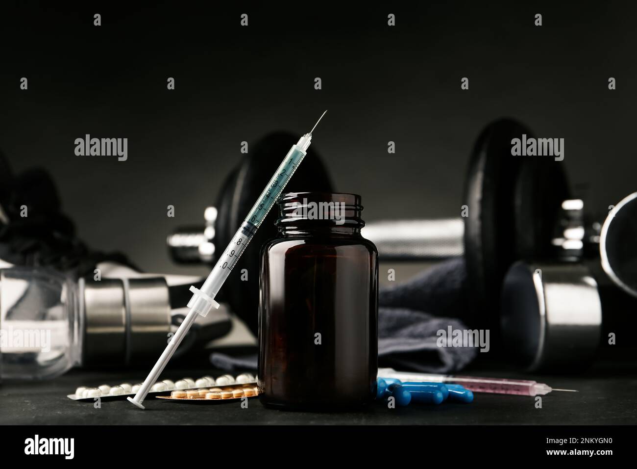 Verschiedene Medikamente in der Nähe von Sportgeräten auf dem schwarzen Tisch. Dopingkontrolle Stockfoto